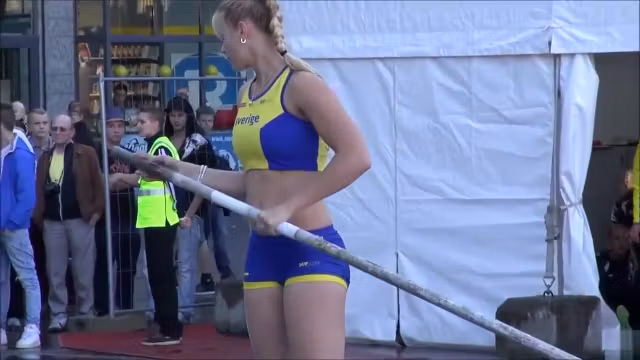 Hot blonde pole vaulter competes at a packed stadium