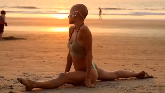 Bald beauty doing yoga by the sea